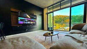 Un soggiorno moderno con un'ampia TV a schermo piatto montata a parete, un tavolino rotondo e un divano.