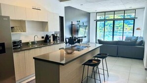 Una cucina moderna con isola centrale, sgabelli da bar e una grande finestra vista su un'area verde.