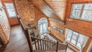 L’intérieur d’un chalet en bois, avec un escalier, des murs en bois et de grandes fenêtres.