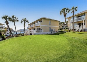 A beachfront hotel with multiple balconies, a pool area, and palm trees. - Paradise By The Pool, pet friendly, beach chairs and umbrella services. (Destin)