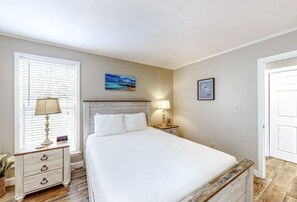 A bedroom with a bed, bedside tables, a nightstand, a window with blinds, and a painting on the wall. - Paradise By The Pool, pet friendly, beach chairs and umbrella services. (Destin)