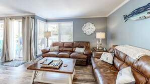 A living room with a brown leather sofa, a wooden coffee table, and a large wall clock. - Paradise By The Pool, pet friendly, beach chairs and umbrella services. (Destin)