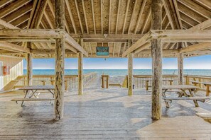 A wooden beach pier with picnic tables and a sign indicating beach access. - Paradise By The Pool, pet friendly, beach chairs and umbrella services. (Destin)