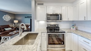 A modern kitchen with white cabinets, a stainless steel microwave, a stove, and an oven. - Paradise By The Pool, pet friendly, beach chairs and umbrella services. (Destin)