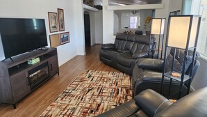 Una sala de estar moderna con un sofá modular, un televisor de pantalla plana, un mueble de entretenimiento de madera y una alfombra estampada.
