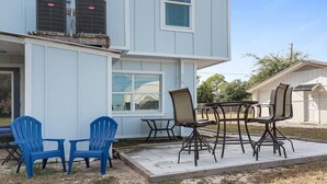 Une maison dotée d’un patio aménagé avec du mobilier d’extérieur et de deux unités de climatisation installées sur le toit.