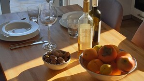 Une table à manger avec des assiettes, des verres à vin, un bol de noix et un bol de fruits.