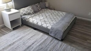 A bedroom with a bed, a nightstand, a lamp, and a rug. - Townhomes Near the Bay - #1 (Grand Bay)