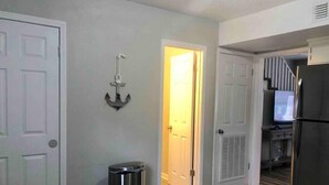A kitchen with a stainless steel refrigerator, a trash can, and a door with an anchor decoration. - Townhomes Near the Bay - #1 (Grand Bay)