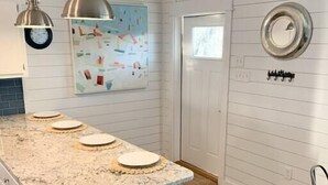 Une cuisine dotée d’un plan de travail en marbre, de luminaires suspendus, d’une poubelle et d’un miroir fixé au mur.
