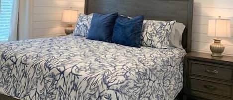Een slaapkamer met een bed, een plafondventilator, een nachtkastje en een wandlamp.