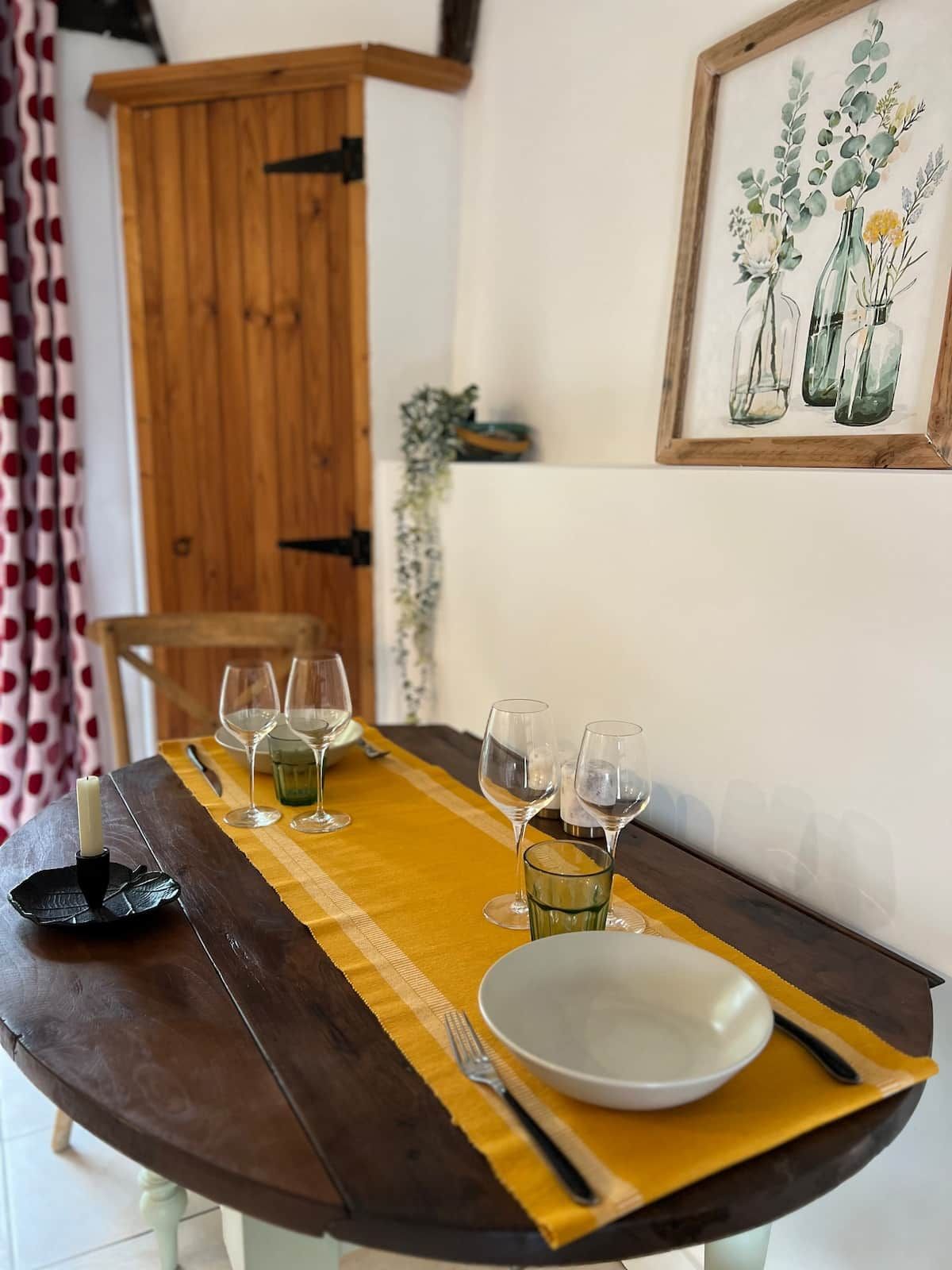 A dining table with a yellow placemat, a white plate, and several wine glasses.