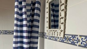 A bathroom with a white sink, a striped shower curtain, and decorative tiles. - La Haye D'armor, Gite au Calme à la Campagne, Animaux de Compagnie Acceptés! (Le Mené)