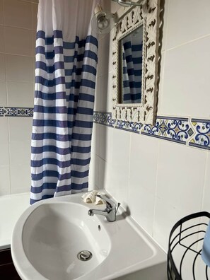 A bathroom with a white sink, a striped shower curtain, and decorative tiles. - La Haye D'armor, Gite au Calme à la Campagne, Animaux de Compagnie Acceptés! (Le Mené)