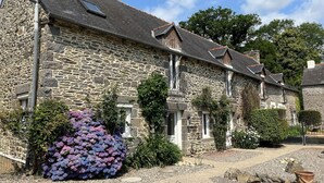 A stone building with a gravel driveway and a large bush of purple flowers. - La Haye D'armor, Gite au Calme à la Campagne, Animaux de Compagnie Acceptés! (Le Mené)