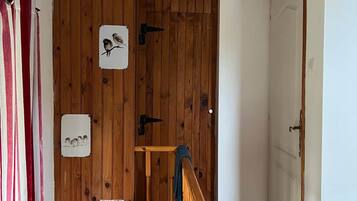 Un escalier en bois avec une rampe, une porte avec une poignée et un mur orné de tableaux encadrés.
