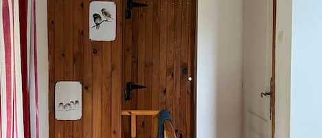 Un escalier en bois avec une rampe, une porte avec une poignée et un mur orné de tableaux encadrés.