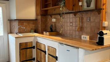Une cuisine avec des meubles de rangement en bois, un évier et une cuisinière intégrée.