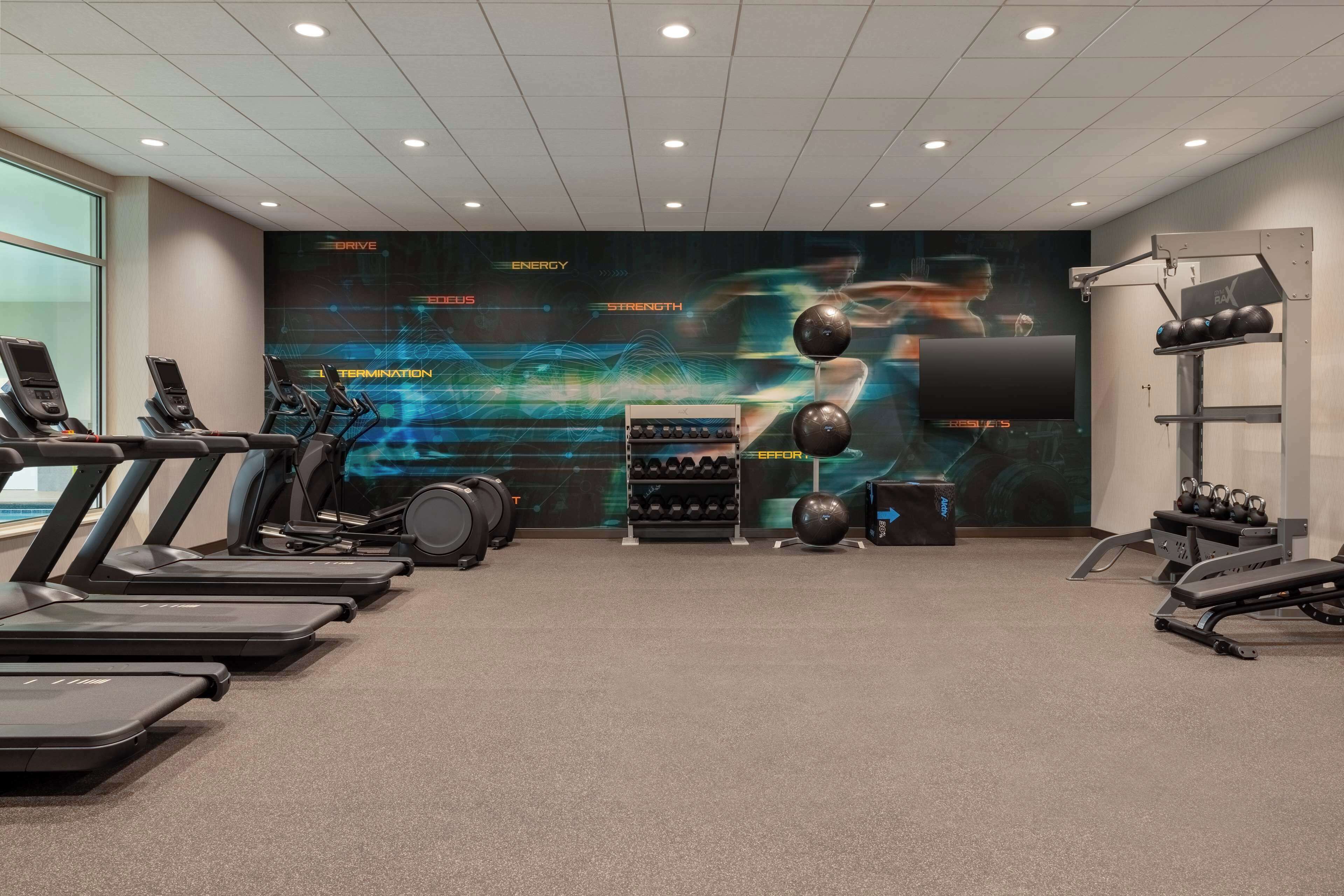 A gym with treadmills, a weight bench, and a wall with motivational graphics.