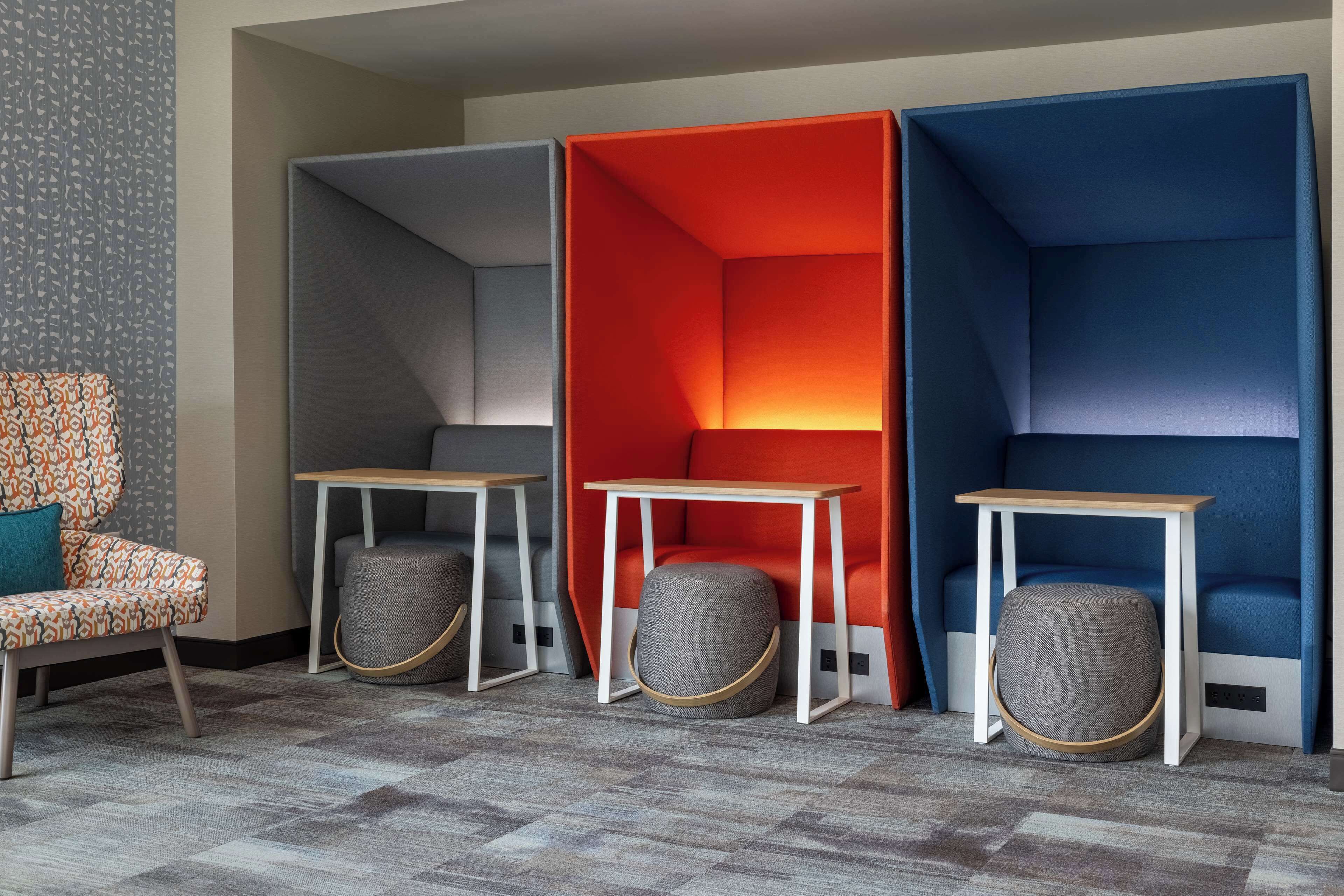 A modern room with a patterned chair, a small table, and three colorful partitions.