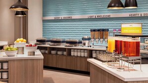 Una barra de desayuno moderna con diversas opciones de comida, como frutas, sándwiches y bebidas.