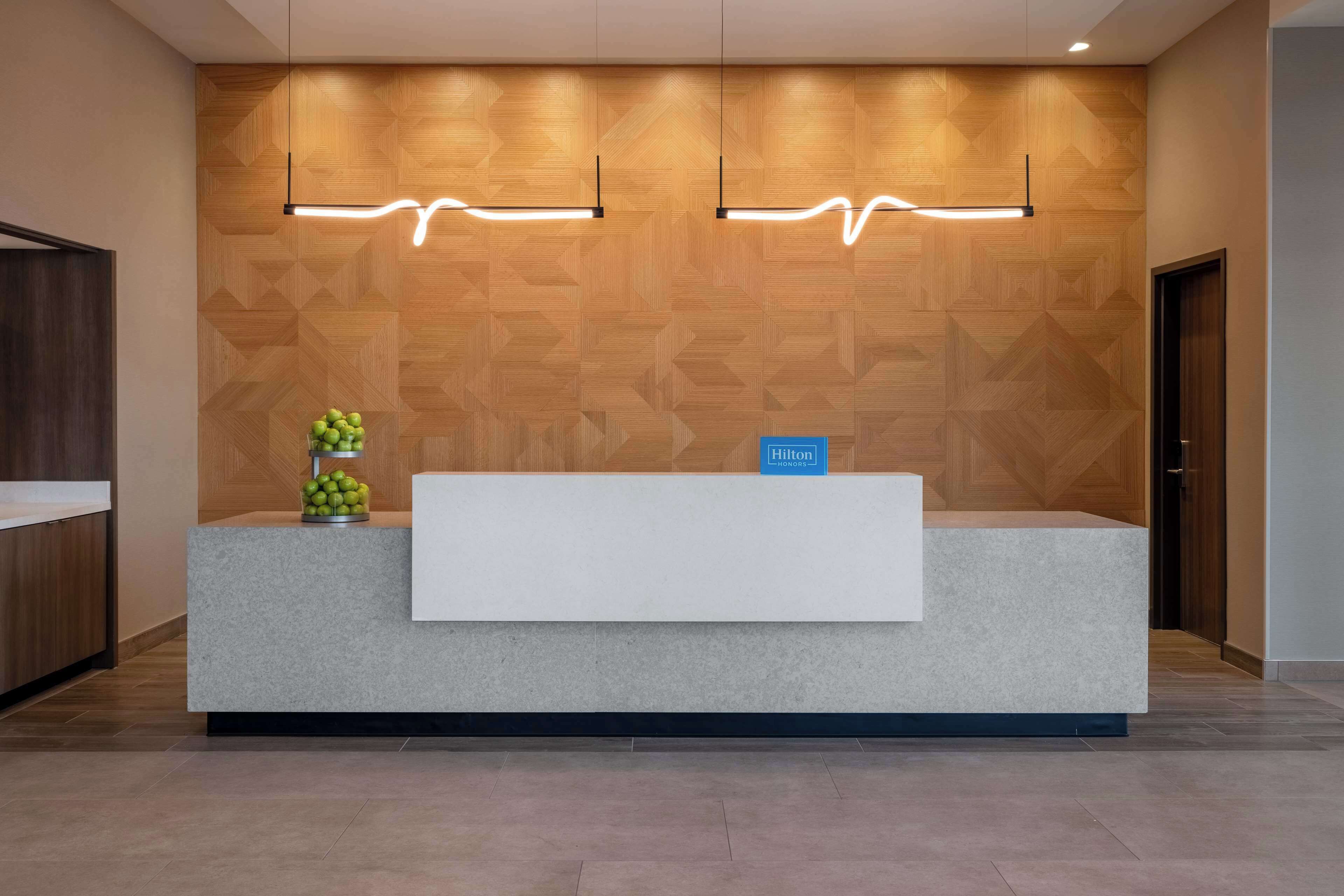 Un mostrador de recepción de hotel con una pared de madera y dos lámparas colgantes.
