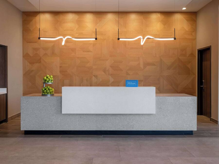 Un mostrador de recepción de hotel con una pared de madera y dos lámparas colgantes.