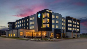 Un hotel moderno con un llamativo letrero de 'TRU by Hilton', varios pisos y una zona de entrada bien iluminada.