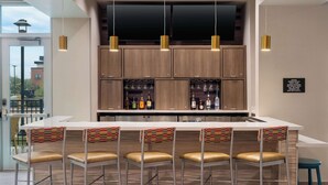 Una cocina moderna con una isla central, taburetes de bar y lámparas colgantes.