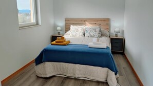Une chambre à coucher avec une tête de lit en bois, une couvre-lit bleue et deux tables de chevet avec des lampes.
