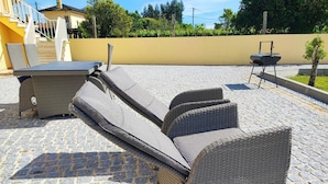 Un espace extérieur aménagé avec des meubles en osier et un barbecue.