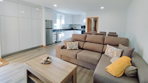 Un salon moderne avec un canapé, une table basse et une cuisine en arrière-plan.