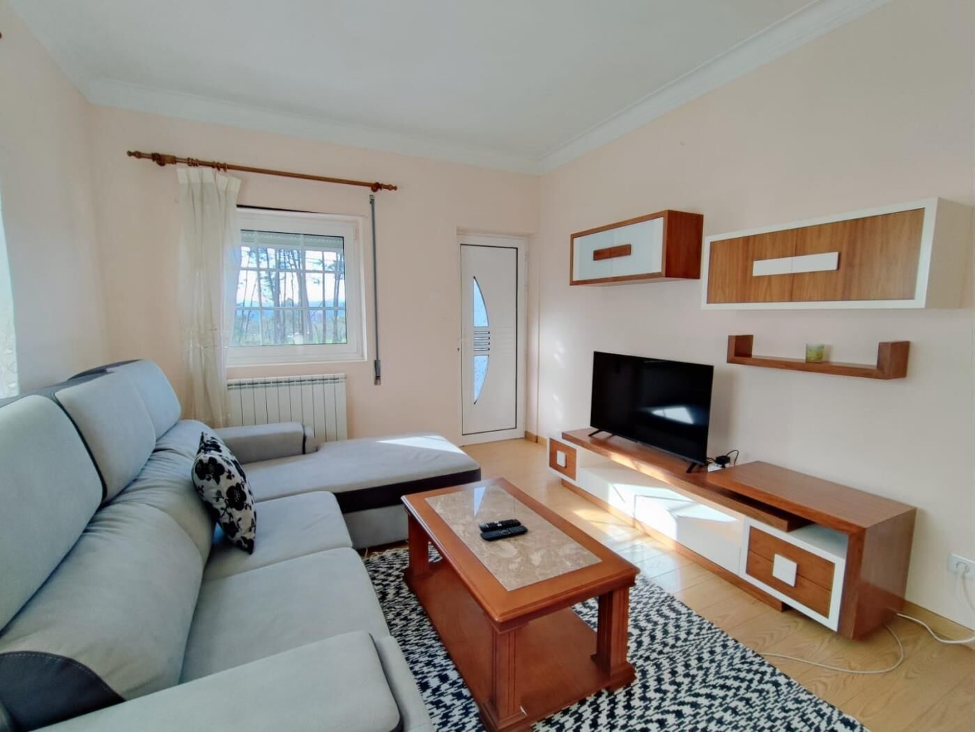 A modern living room with a sofa, a coffee table, a TV, and a wooden cabinet.