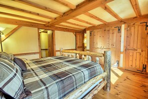Ein Schlafzimmer mit Holzbett, einer Holzbank und einer Tür.