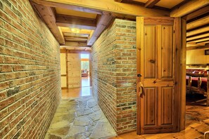 A narrow hallway with brick walls and a wooden door.