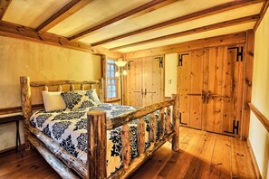 A rustic bedroom with a wooden bed, a nightstand, and a window. - Western Lodge - Huge, w/Heated Pool, Hocking Hills (Logan)