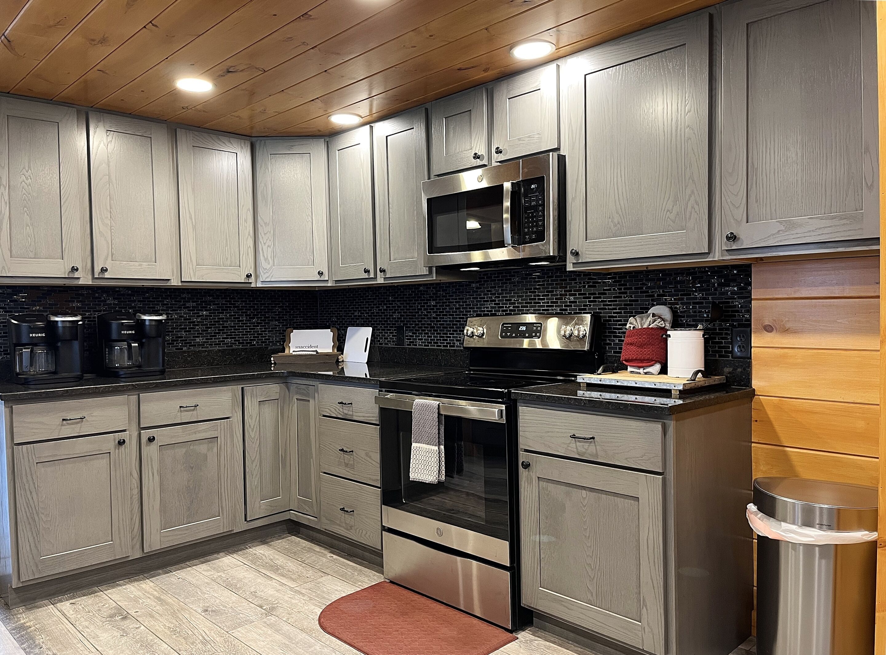 A modern kitchen with wooden cabinets, a stainless steel refrigerator, a microwave, and a coffee maker.