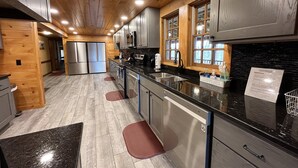 A modern kitchen with stainless steel appliances, wooden cabinets, and a black countertop.