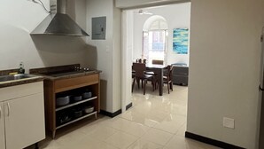 A kitchen with a gas stove, a range hood, and a dining area with a table and chairs.