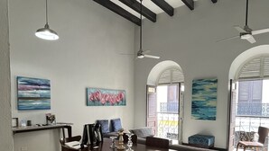 A spacious dining area with a wooden table and chairs, a sofa, and artwork on the walls.
