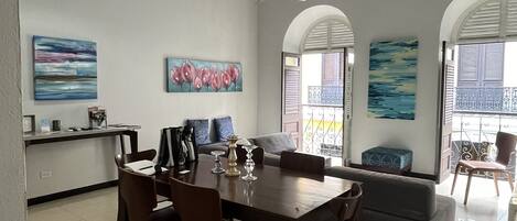 Un vaste espace dédié à la salle à manger, avec une table et des chaises en bois, un canapé et des œuvres d’art accrochées aux murs.