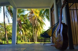 A covered outdoor area with a hammock and a guitar, surrounded by palm trees. - Hotel Pura Natura Beachfront Tortuguero (Colorado)
