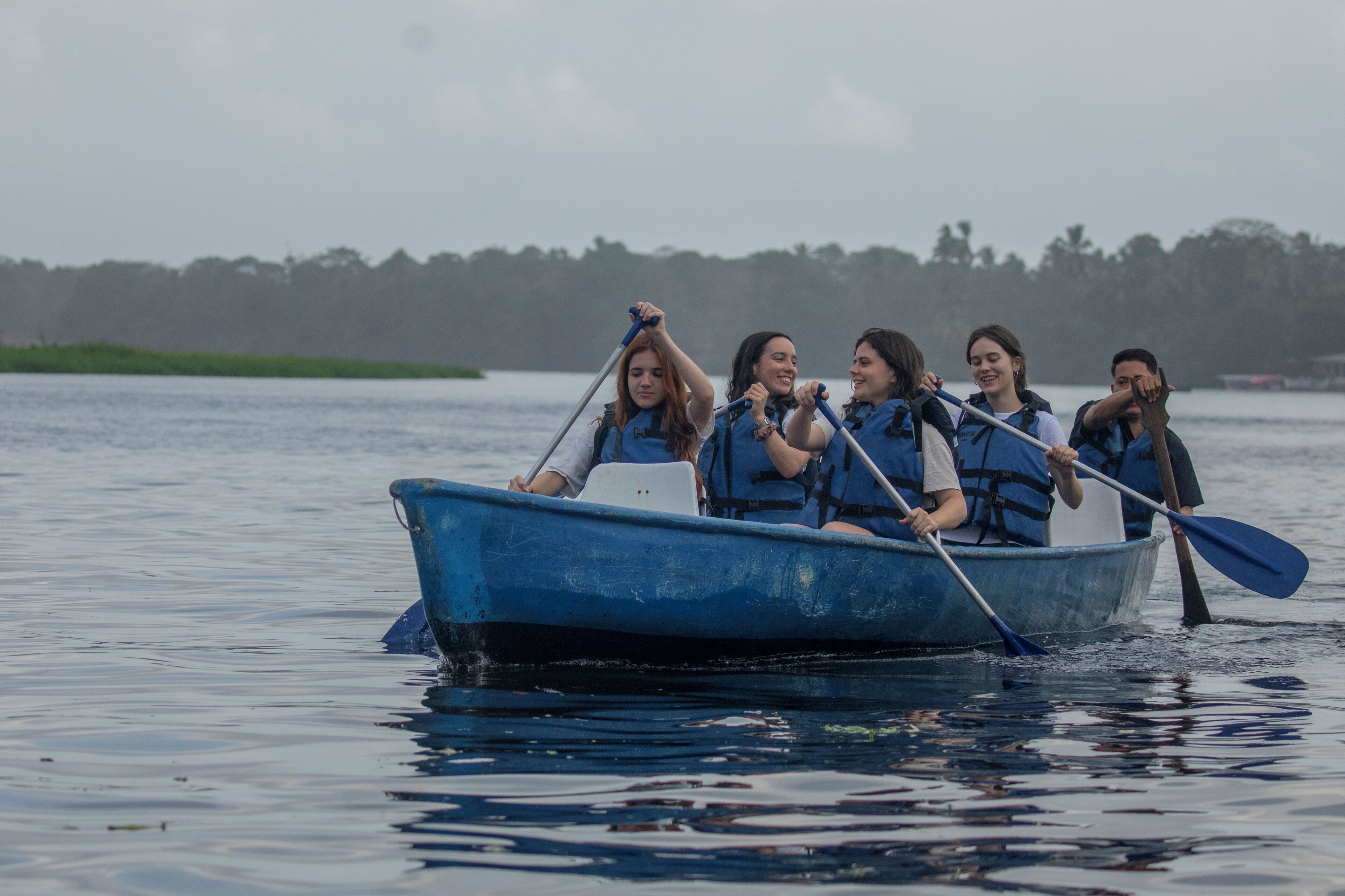 A group of people in a blue boat on a calm body of water.