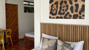 A bedroom with a bed, pillows, a wooden headboard, a window, and a door. - Hotel Pura Natura Beachfront Tortuguero (Colorado)