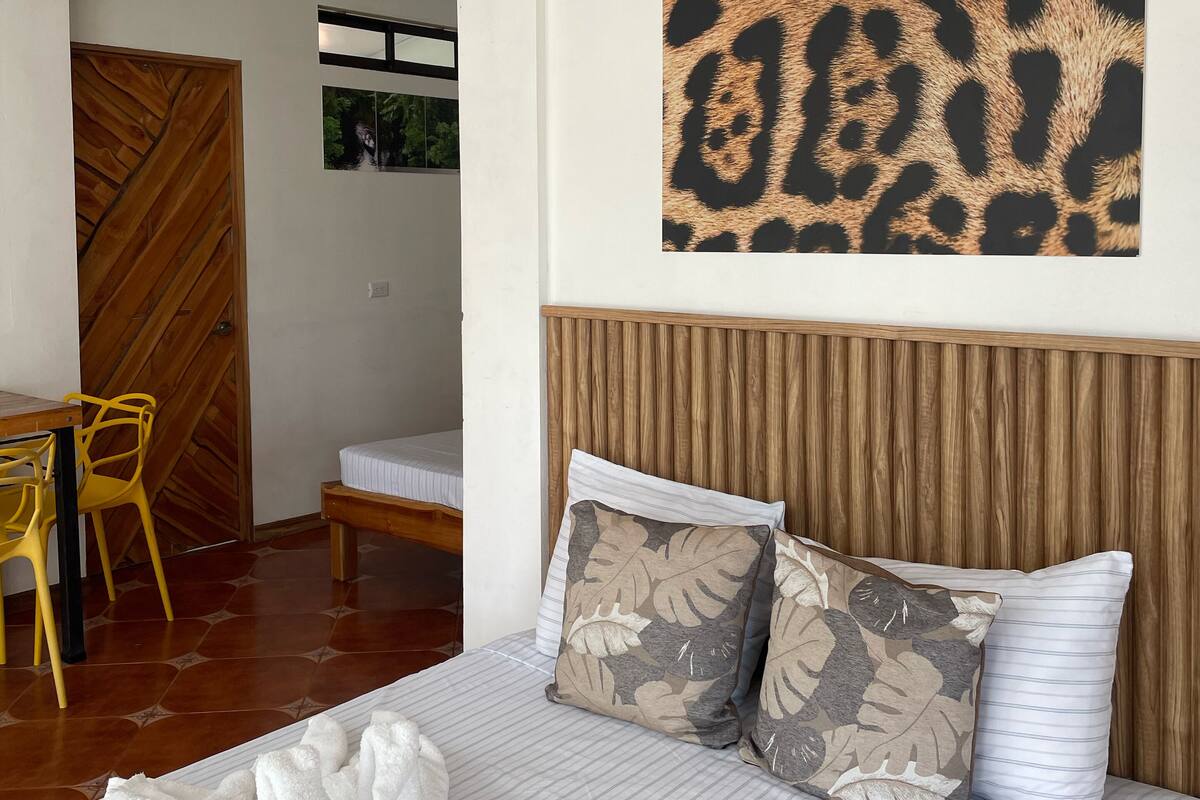Une chambre à coucher avec un lit, des oreillers, une tête de lit en bois, une fenêtre et une porte.