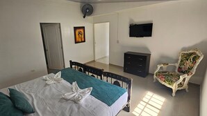 Una habitación de hotel con una cama, una silla, un televisor y un armario.