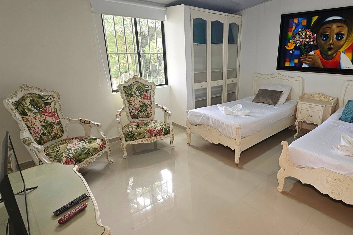 Un dormitorio con dos camas, una silla, un armario y un cuadro en la pared.