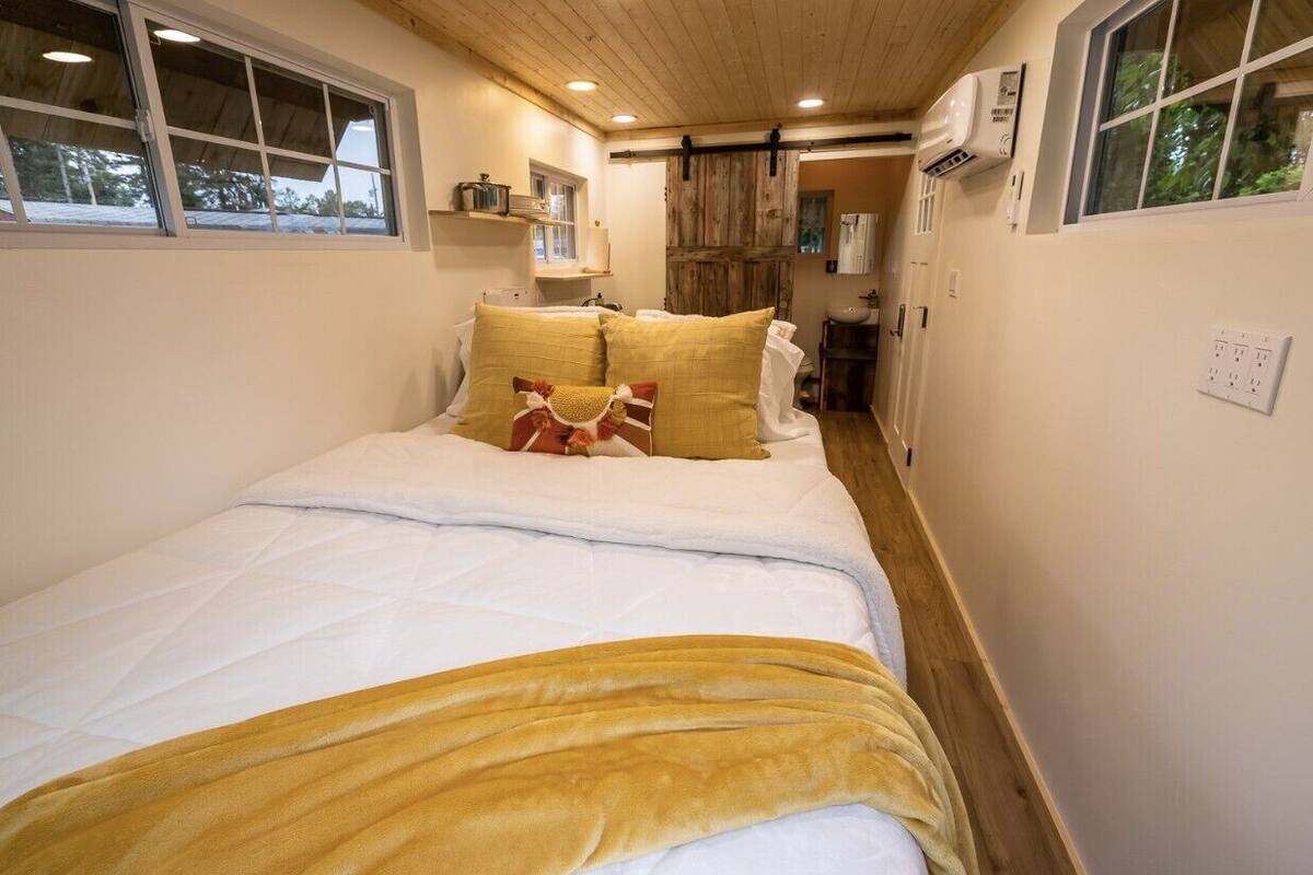 A narrow, cozy bedroom with a bed, pillows, and a window.