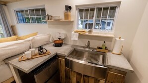 Una cocina compacta con lavavajillas integrado, pileta de acero inoxidable, detalles de madera y ventana con vista.