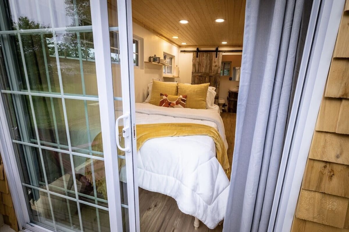 A bedroom with a bed, a window, and a door.